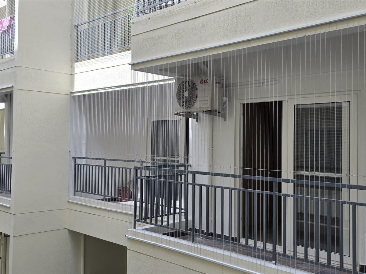 Invisible grill wires installed across multiple balconies on an apartment building exterior