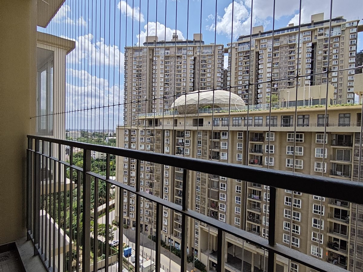 Invisible grill wires on a balcony overlooking a tall apartment block