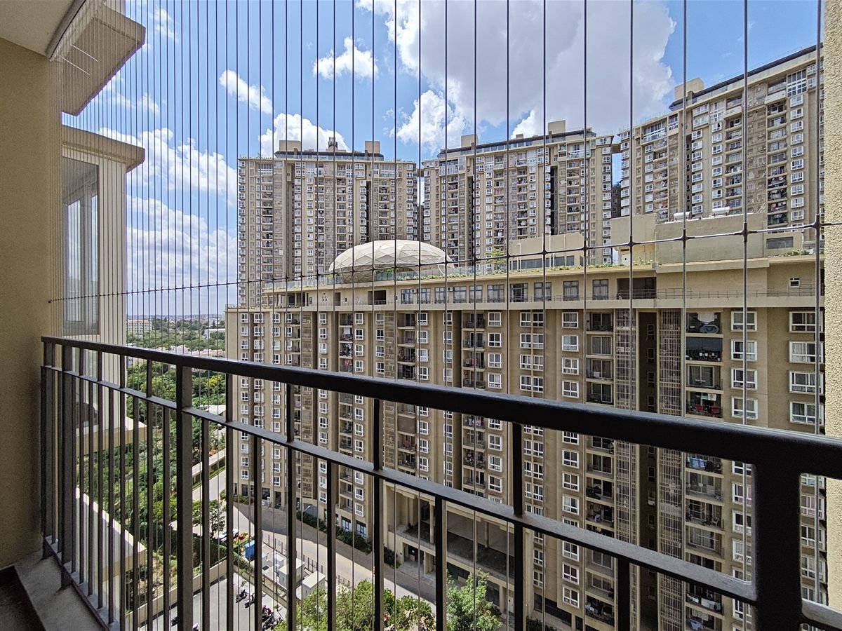 Invisible grill wires installed on a high-rise apartment balcony, overlooking a dense residential complex