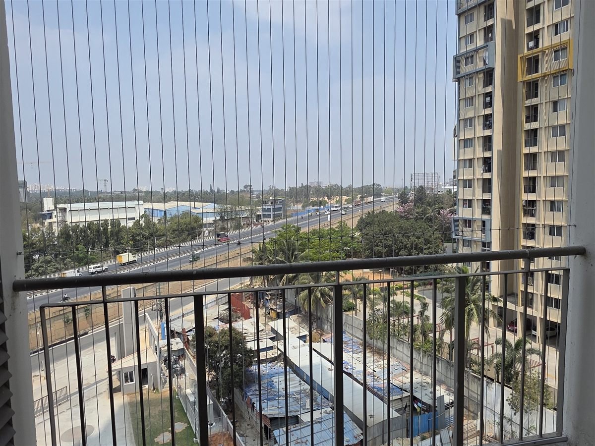 Invisible grill wires on a balcony overlooking a highway and apartment towers