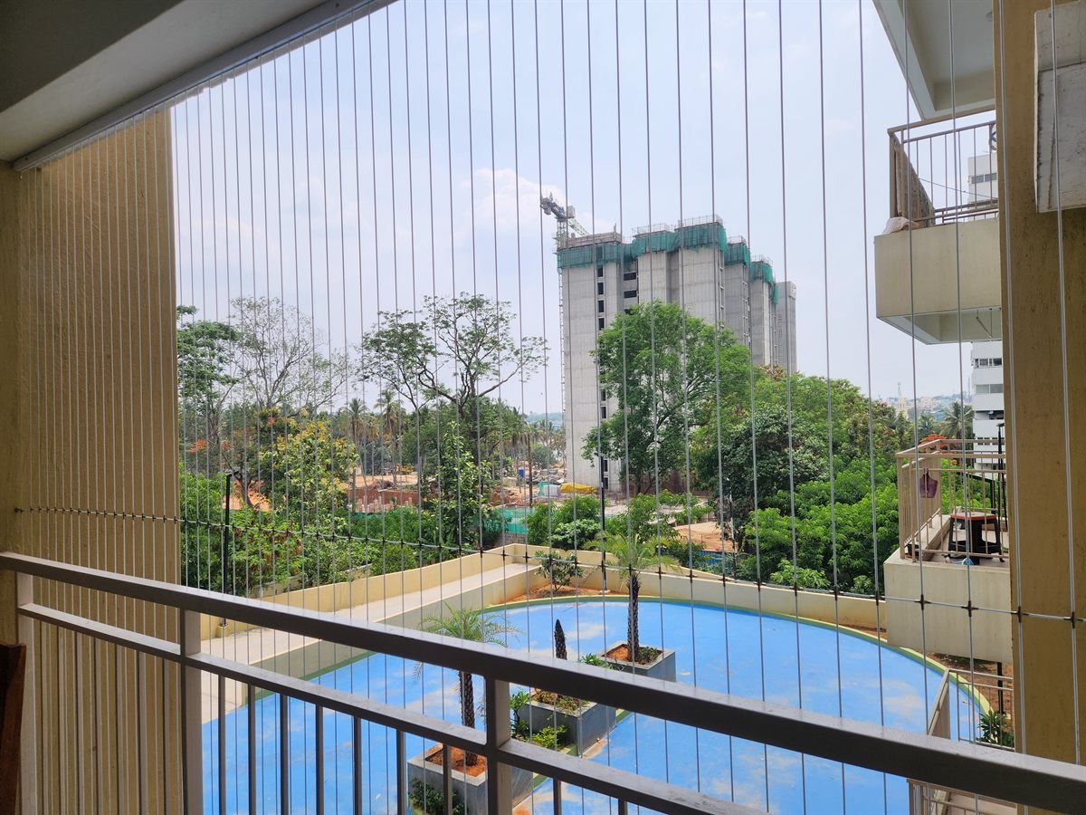 Invisible grill wires on a balcony overlooking a residential complex swimming pool