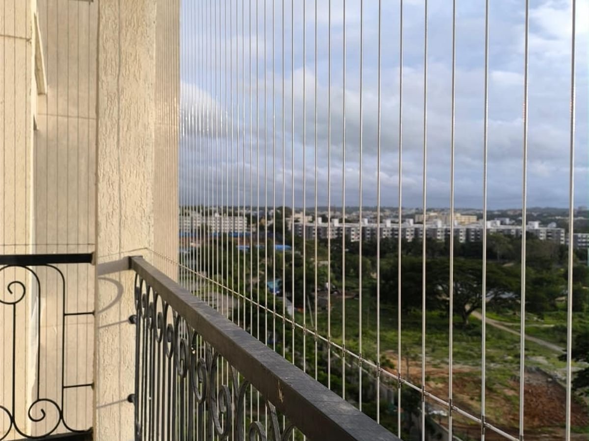 Tensioned invisible grill wires fixed against a wrought-iron balcony railing