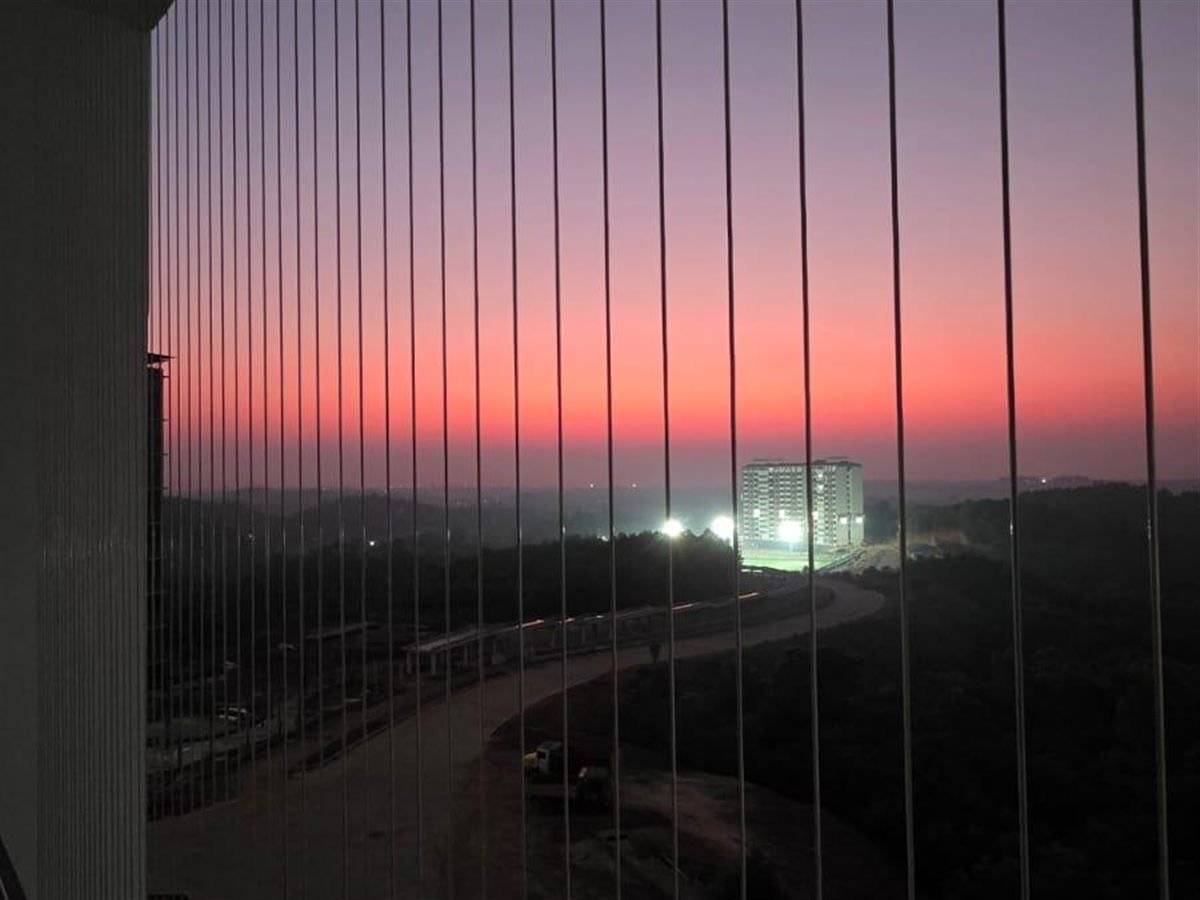 Invisible grill wires on a high-rise balcony overlooking the skyline at twilight
