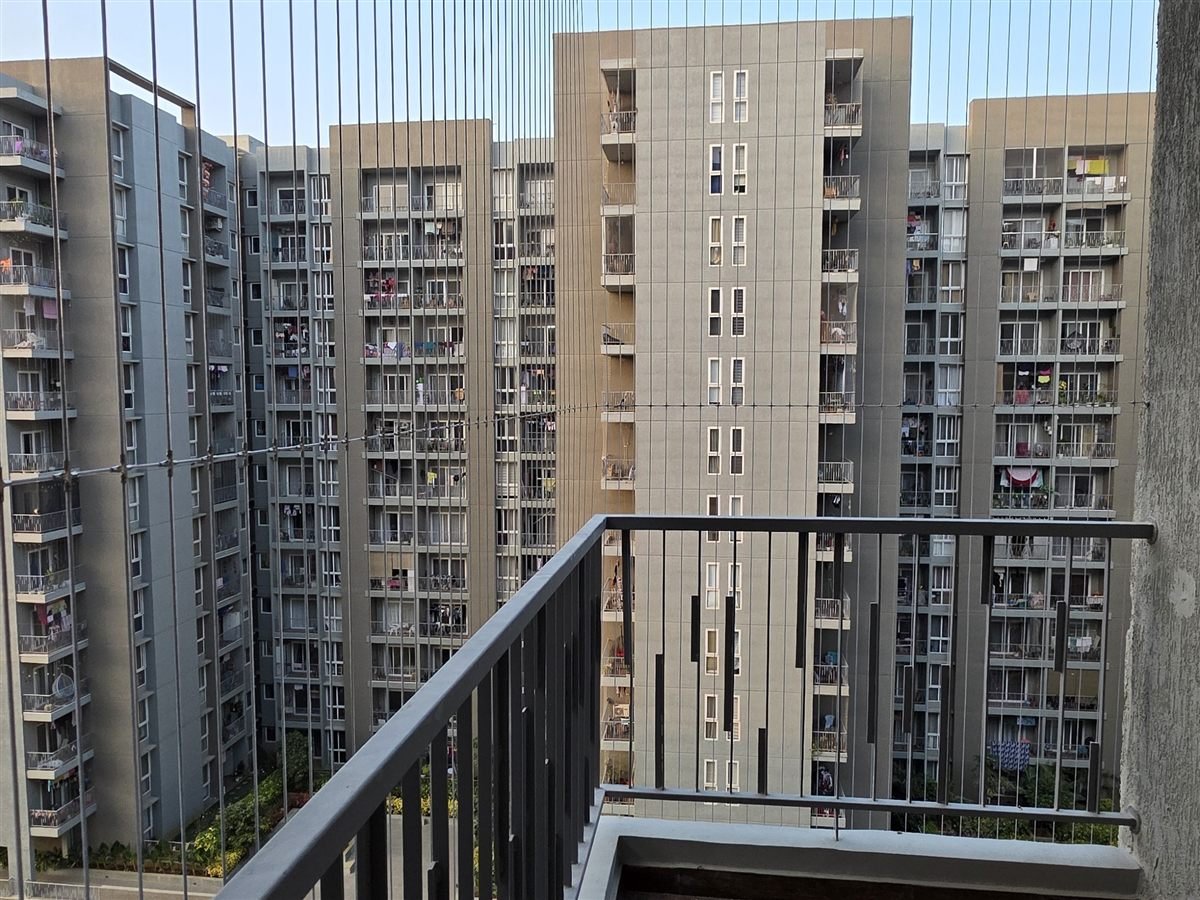 Invisible grill wires on a balcony facing a dense cluster of high-rise apartment towers