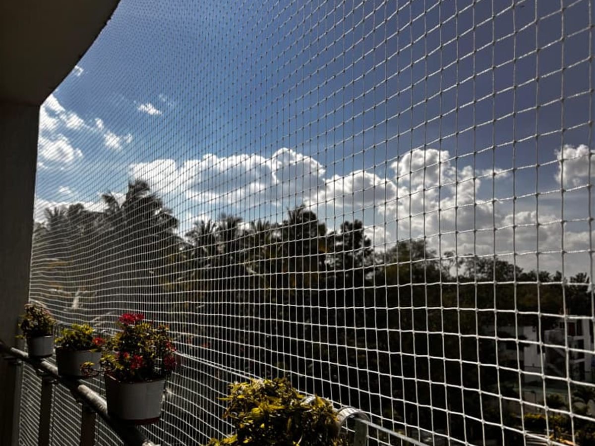 Pigeon net installed on a balcony with potted plants along the railing